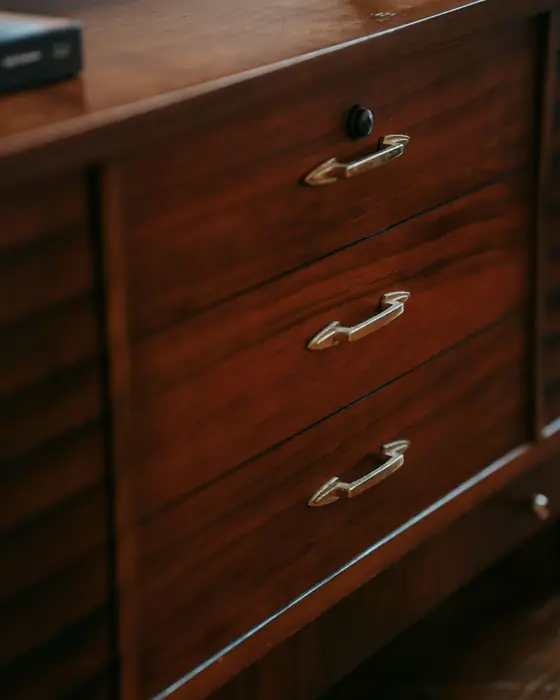 Dark timber drawer fronts fitted with slim aged brass pull handles.